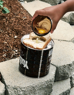 1) Butter a piece of bread on both sides.  2) Cut a circle from the center of the bread slice, using a cookie cutter or the top of another can.  3) Place the buttered bread on the hot hobo stovetop, break an egg into the hole, and sprinkle with salt and pepper to taste.