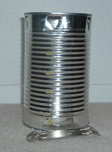 5. Turn the 3-pound coffee can upside down. Use the can opener to punch triangular holes at intervals below the bottom of the can, which has of course now become the top of the can. The holes at the stove’s top will allow oxygen to feed the lighted burner below. The holes don't show up well on the dark coffee can, so we're using a juice can here to illustrate.