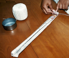 1. Fold a newspaper page in half, then fold it in half again, creasing well, and repeat until you have a strip narrow enough to fit just below the rim of the tuna can when it’s rolled up and placed on edge inside the can. Make several of these strips.