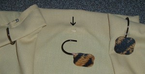 LEFT: All along the side of the tablecloth that will be the top of the curtain, fold back 2 inches of fabric. Fasten with a safety pin at each point where you want a hook to go. CENTER: The arrow points to the safety-pin shaft visible on the front of the curtain. RIGHT: Slip the hook under the safety-pin shaft, pull it through, and voila! you're ready to hang the curtain—with no holes to prevent you from using the fabric in a different way later.